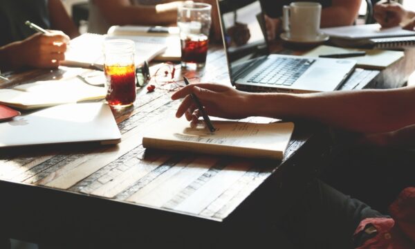 people working at table with notebooks and laptop