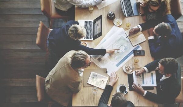 workers at table pointing at paper