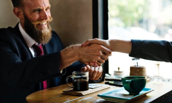 man shaking hands at table with coffee