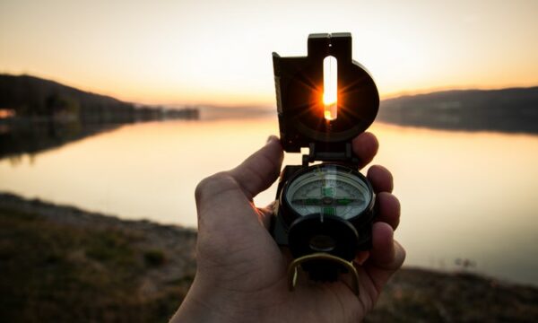 compass in front of lake and sun