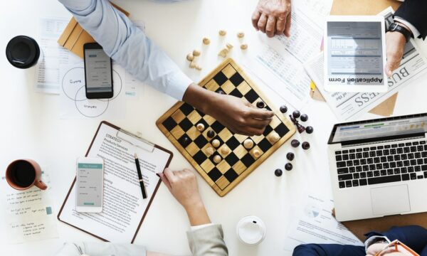 playing chess on table surrounded by report sheets