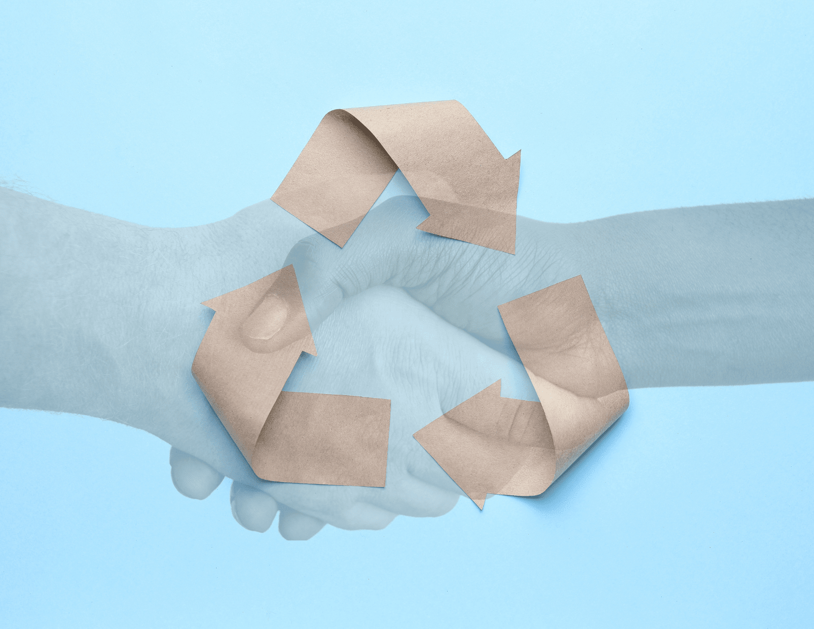Sky blue background with recycling logo laid out in brown paper, with a transparent image of two hands shaking overlaid (one white, one Black)