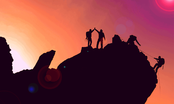 Three hikers in silhouette helping pull a fourth hiker up the side of a mountain, with a orange and pink sunset in the background.